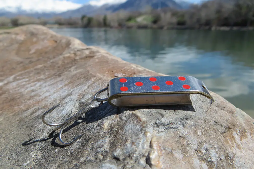 silver jakes fishing spoon sitting on a rock by the river